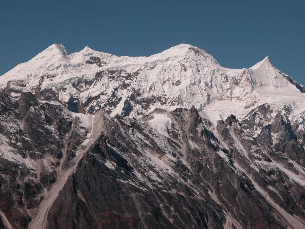 Manaslu 09 06 Kang Guru From Descent From Larkya La Just after starting the descent from the Larkya La, the vista opened up with Kang Guru (6981m, also called Naurgaon) sticking up above an intervening ridge. Kang Guru was first climbed on July 2, 1955 by Germans Heinz Steinmetz, Fritz Lobbichler, and Juergen Wellenkamp. The worst disaster for an expedition in Nepal occurred on October 20, 2005 when seven French and 11 Nepalese, who were in their Kang Guru base camp tents after late afternoon tea, were swept away by a huge avalanche into a deep gorge below.